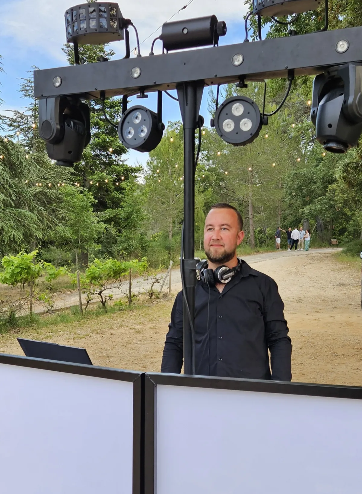Nico derrière ses platines, casque autour du cou, sous son portique d'éclairage lors d'un événement en plein air